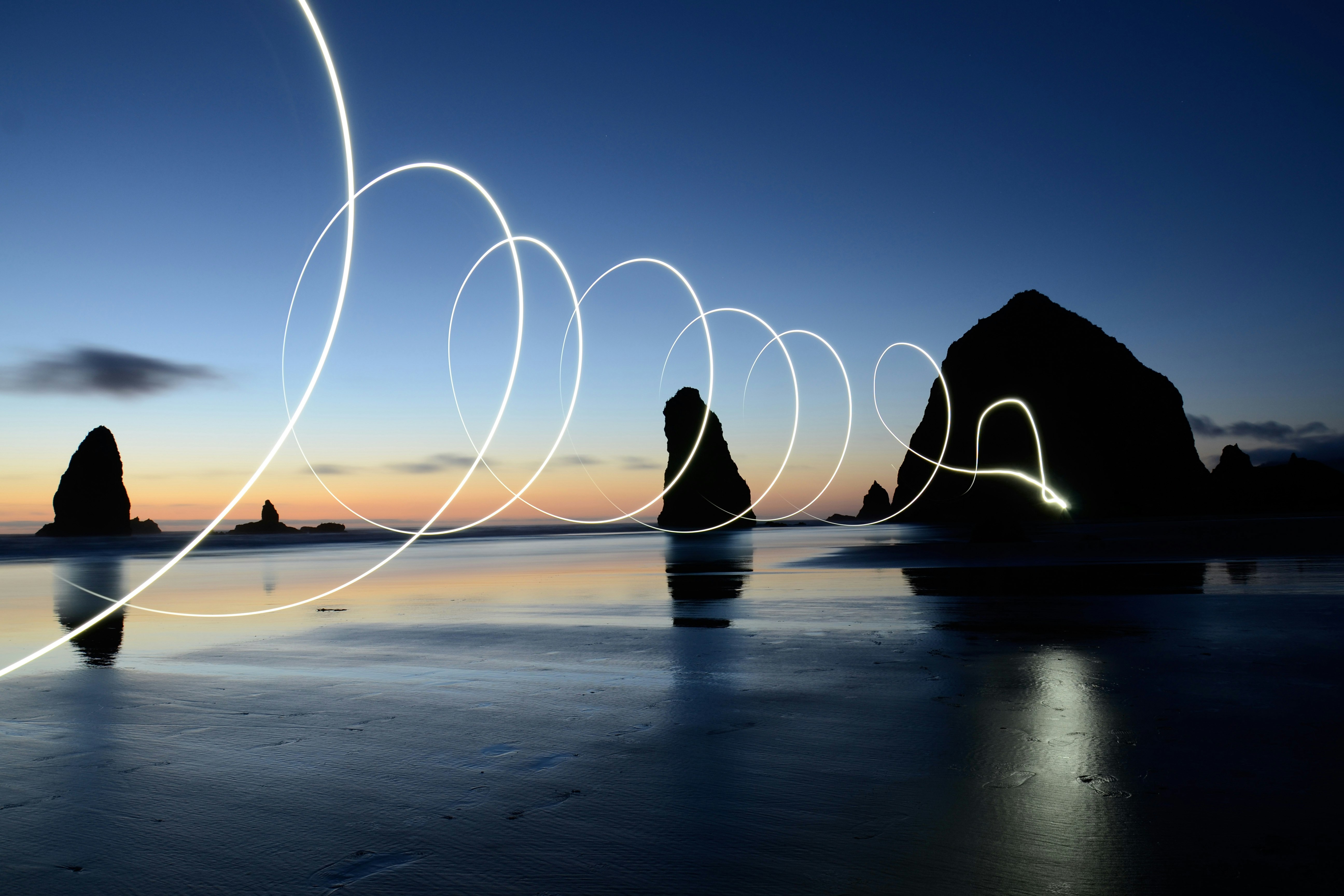 photo of rock formation on body of water at nighttime